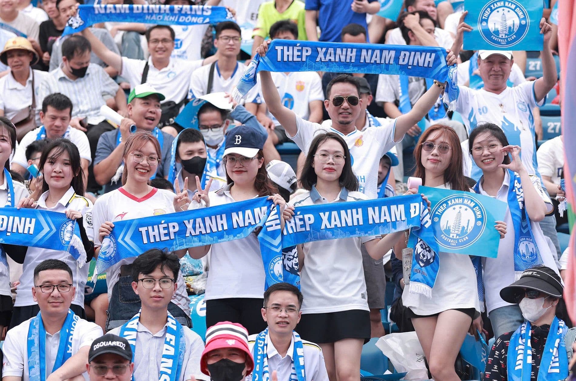 A group of fans celebrating with a banner or flag after their team wins a game.