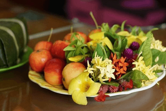 Đĩa trái cây và hoa tươi được bày biện cẩn thận, tượng trưng cho sự cầu mong may mắn và thịnh vượng cho gia đình trong tháng mới.
