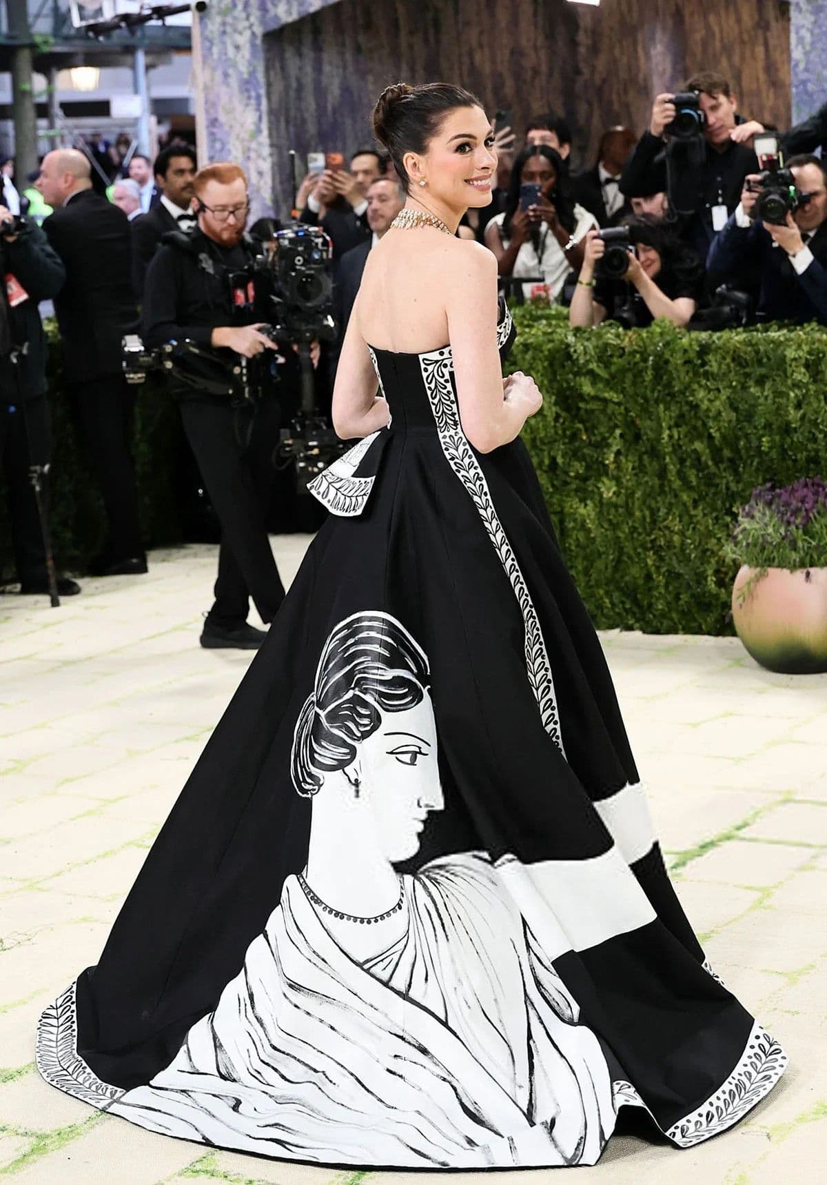 Anne Hathaway trong chiếc váy dạ hội đen trắng với hình ảnh nghệ thuật trên tà váy, thể hiện ngôn ngữ kể chuyện của trang phục tại Met Gala.