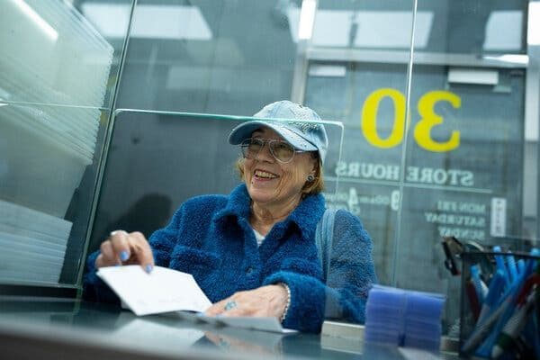 Bà Jennifer Tessler vui mừng nhận séc 7.338 USD sau khi bán trang sức vàng gia truyền tại Bullion Exchanges.