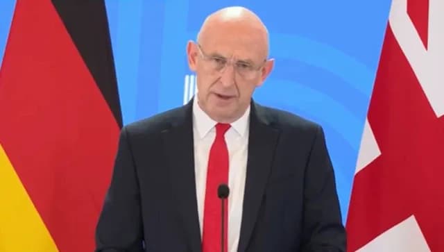 Bộ trưởng Quốc phòng Anh Healey phát biểu trước cờ Đức, thể hiện sự đoàn kết và hỗ trợ của các đồng minh NATO.