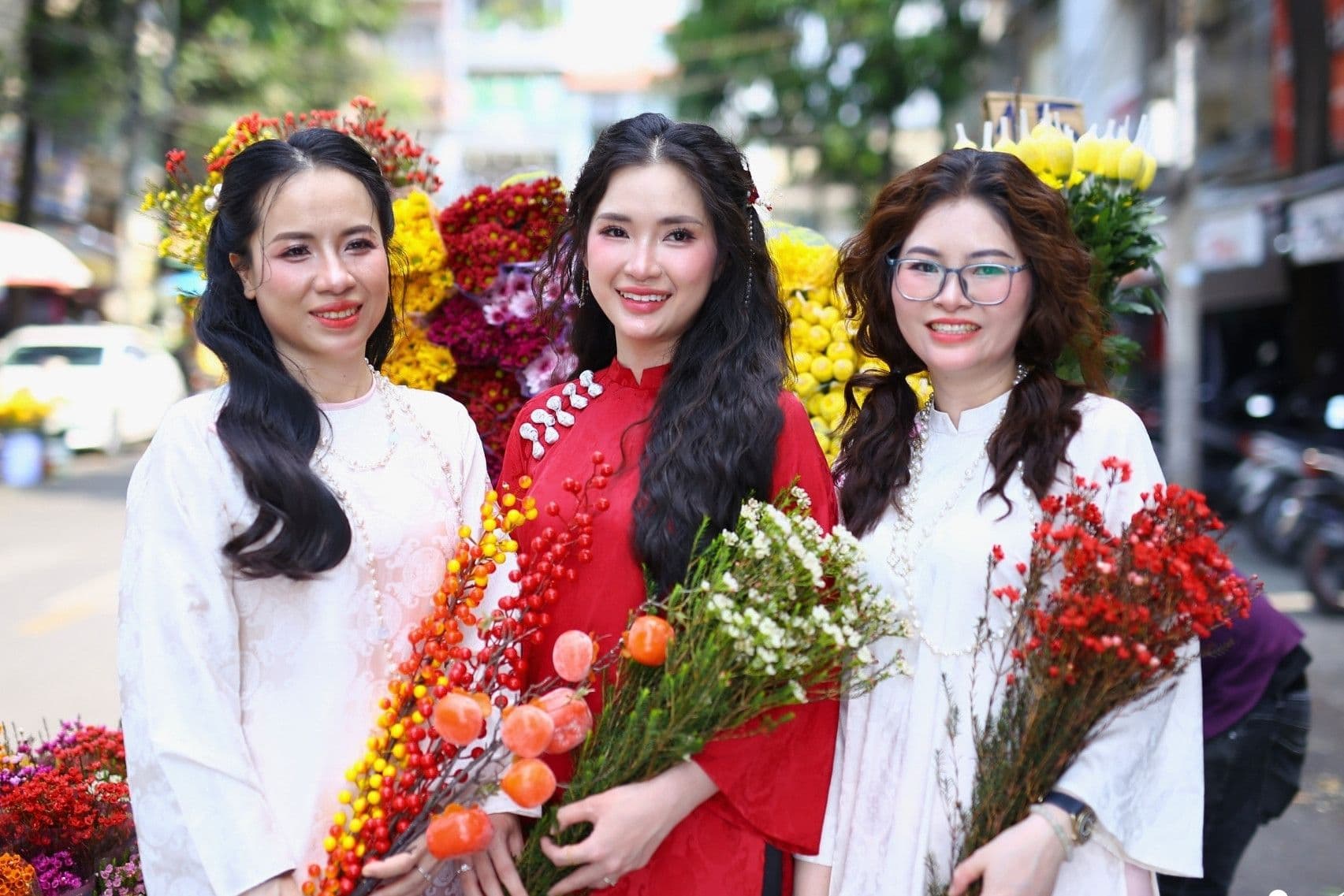 Ba người phụ nữ tươi cười cầm những bó hoa tươi thắm, chuẩn bị cho các nghi lễ và hoạt động gieo mầm may mắn ngày Lập Xuân.