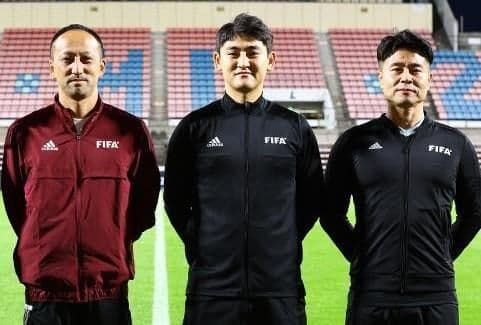 Ba trọng tài FIFA đứng trên sân cỏ, tượng trưng cho tính chuyên nghiệp và sự công bằng trong điều hành các trận đấu bóng đá châu Á.
