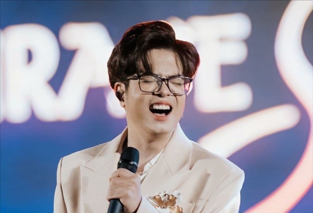 Bùi Anh Tuấn đang biểu diễn trên sân khấu với biểu cảm xúc động, tay cầm micro