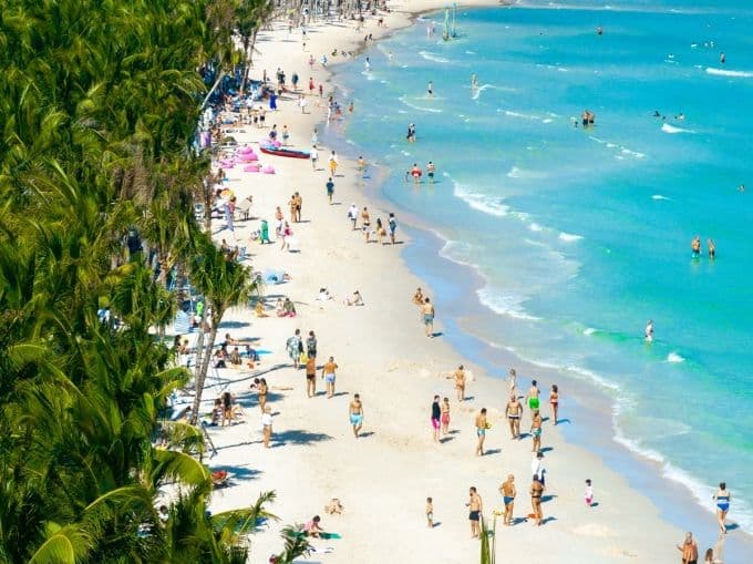 Bãi biển Phú Quốc với bờ cát trắng và hàng dừa xanh, thu hút đông đảo du khách tắm biển và vui chơi.