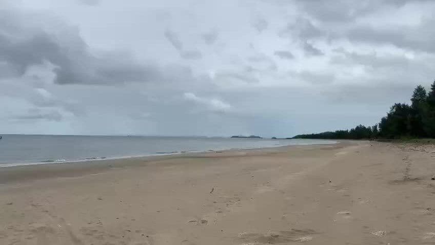 Bãi biển yên bình dưới bầu trời nhiều mây, tượng trưng cho sự suy yếu của bão Ragasa và không gây thiệt hại