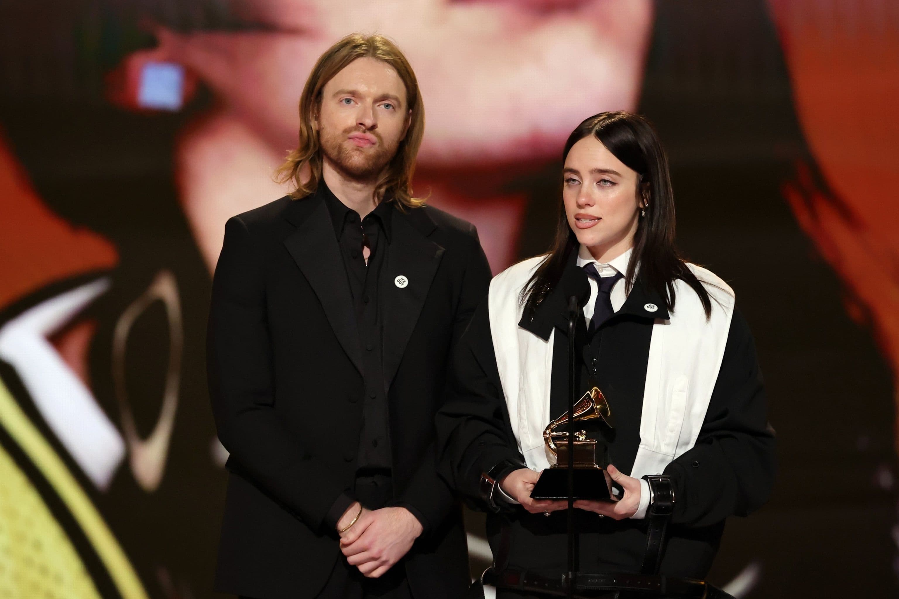 Billie Eilish và Finneas O'Connell cầm giải Grammy, Billie đeo ghim 'ICE Out' trên ve áo.