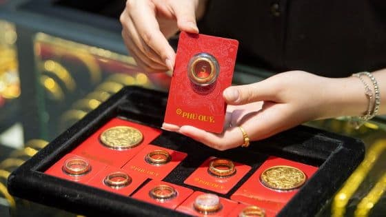 Bàn tay đang cầm thẻ vàng và các nhẫn vàng, minh họa cho việc giữ lộc và tích lũy tài sản.