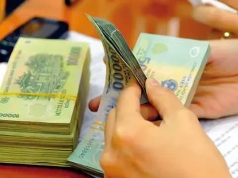 Bàn tay đang kiểm đếm các cọc tiền Việt Nam đồng, thể hiện việc chi trả tiền thưởng Tết từ doanh nghiệp.