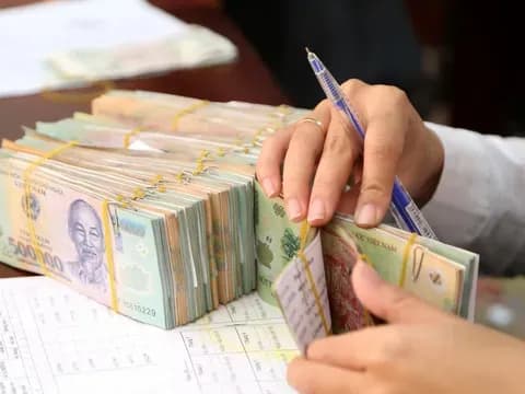 Bàn tay đang kiểm tra các cọc tiền Việt Nam đồng, minh họa việc chi trả 500.000 đồng tiền mặt theo Kế hoạch 341 cho các hộ gia đình dịp Tết.