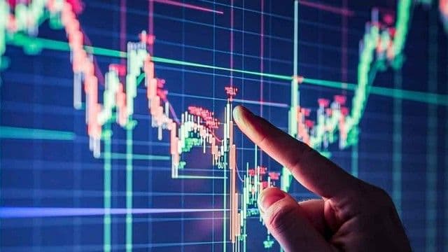 Bàn tay chỉ vào biểu đồ chứng khoán thể hiện sự phân tích dữ liệu tài chính và biến động thị trường.