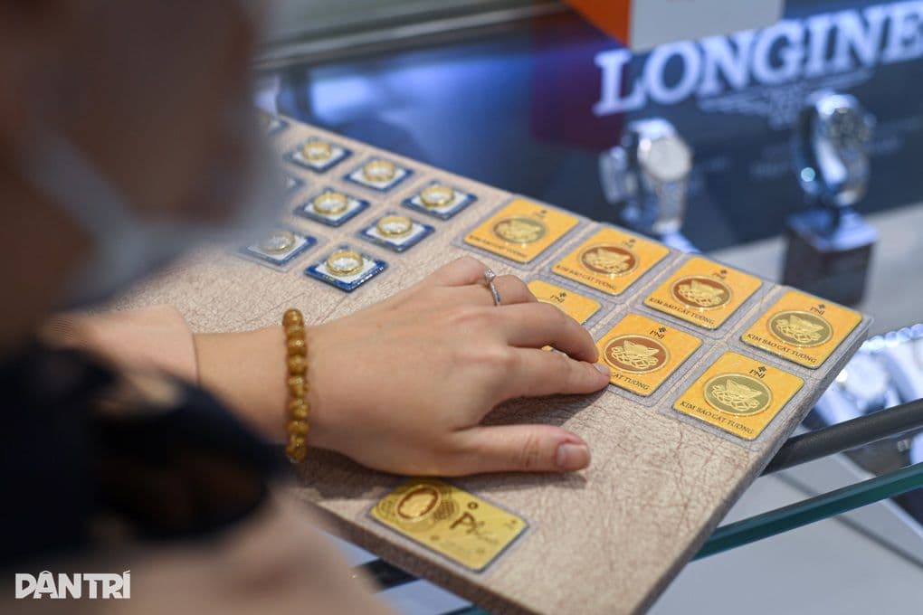 Bàn tay chỉ vào các sản phẩm vàng miếng và vàng thẻ, thể hiện sức hút bất biến của kim loại quý trong bối cảnh bất ổn toàn cầu