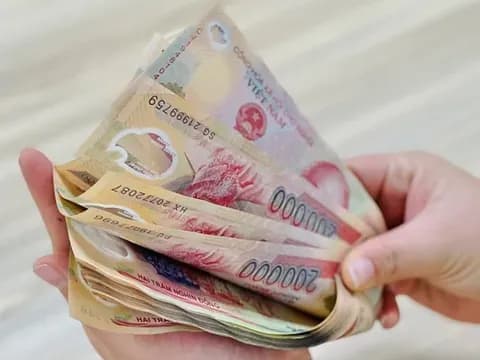 Bàn tay cầm xấp tiền Việt Nam đồng, tượng trưng cho tiền thưởng Tết và thu nhập bổ sung cho người lao động.