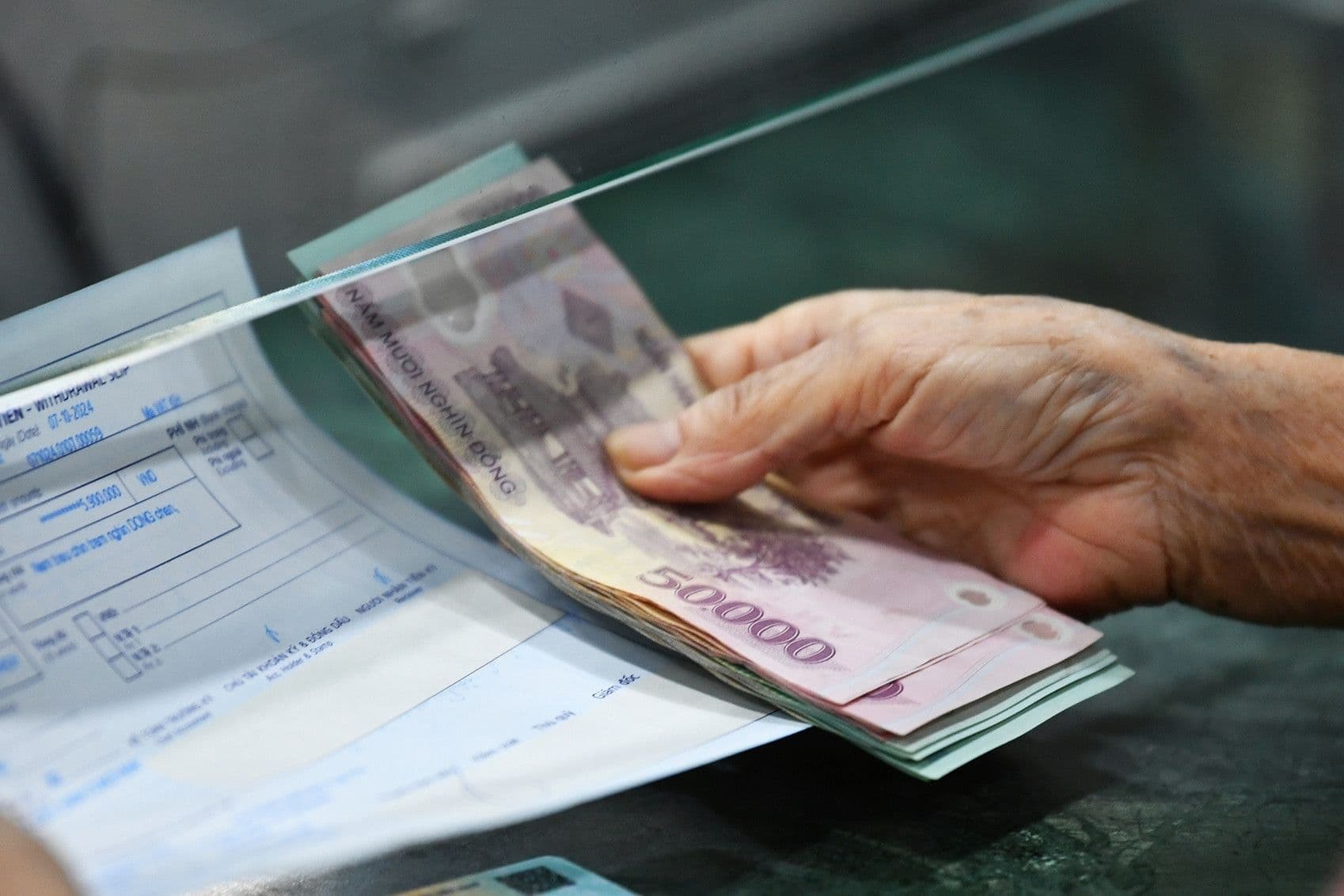 Bàn tay người cao tuổi nhận tiền trợ cấp, thể hiện tầm nhìn về hỗ trợ tài chính trong xã hội "Tuổi Vàng".