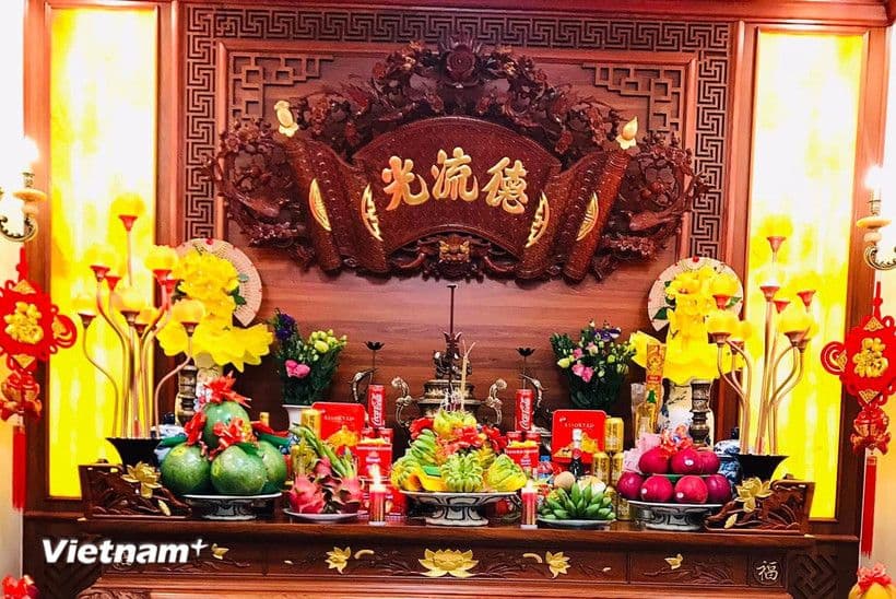 Bàn thờ cúng ông Công ông Táo với hoa tươi, quả ngọt và nén hương, thể hiện lòng thành kính và ước nguyện bình an.