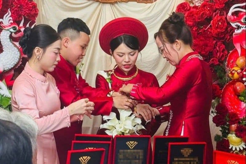 Cô dâu trong trang phục cưới truyền thống Việt Nam nhận trang sức trong lễ ăn hỏi, thể hiện nghi thức truyền thống.