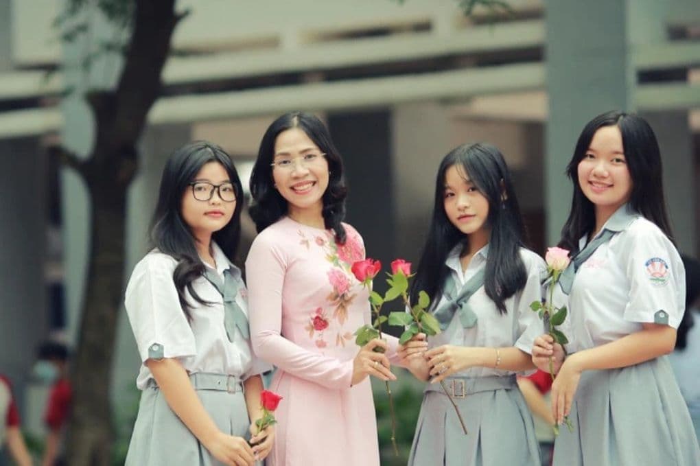 Cô giáo và học sinh tươi cười nhận hoa trong Ngày Phụ Nữ, thể hiện sự trân trọng và yêu thương
