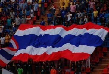 Cổ động viên Thái Lan với lá cờ lớn, tượng trưng cho tinh thần bóng đá Đông Nam Á trong cuộc đối đầu với các cường quốc Đông Á.
