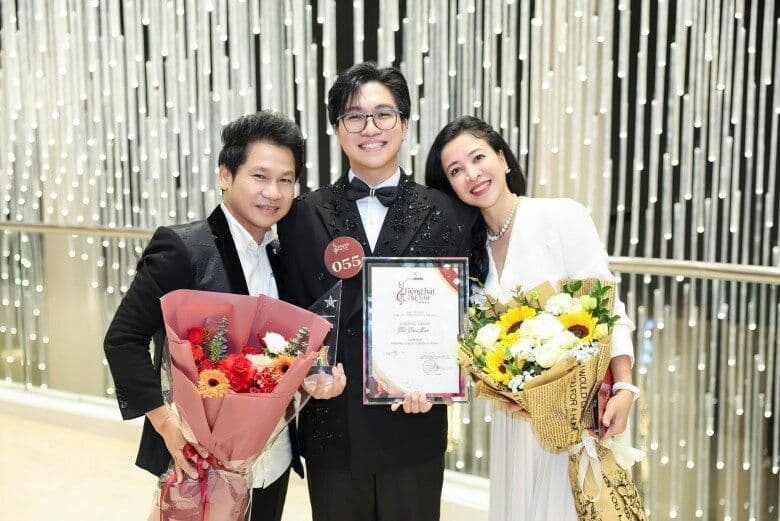 Ca sĩ Tấn Đạt cầm bằng khen và cúp, đứng giữa bố Trọng Tấn và mẹ, thể hiện thành công bước đầu trên con đường nghệ thuật.