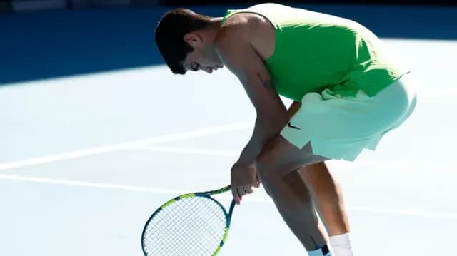 Carlos Alcaraz cúi người, thể hiện sự mệt mỏi và áp lực trên sân đấu