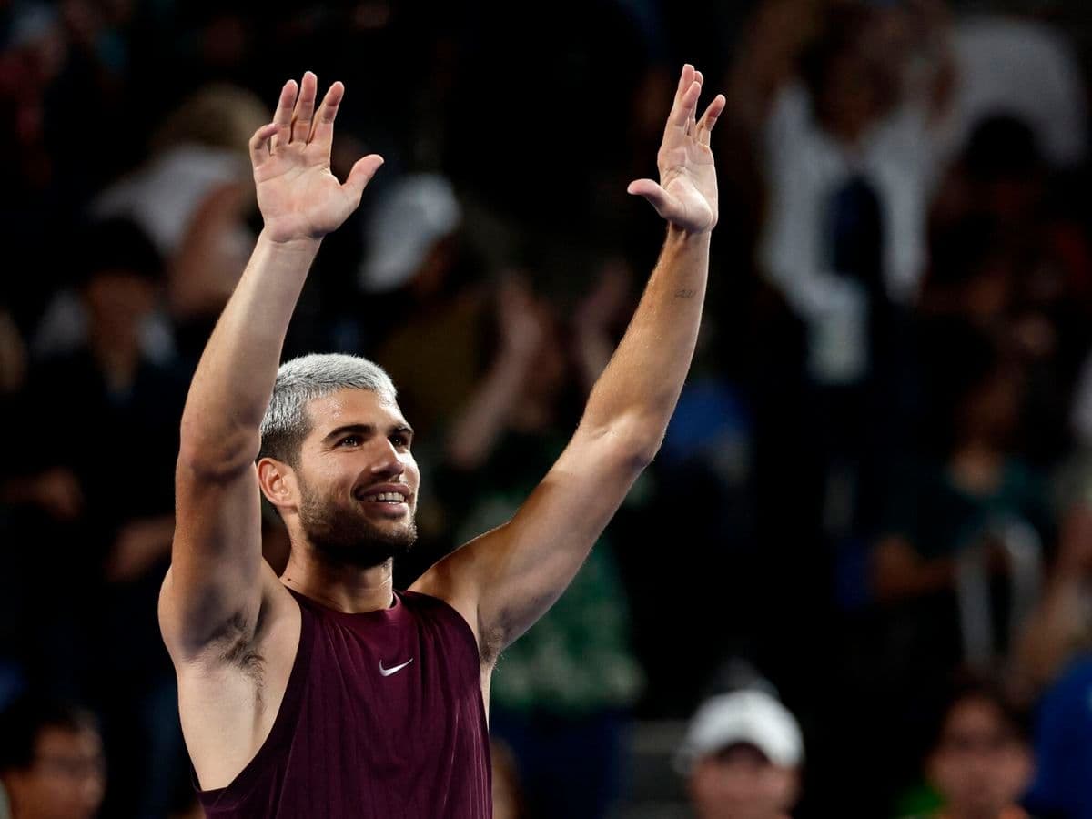 Carlos Alcaraz giơ tay chào khán giả sau một chiến thắng tại ATP Tokyo, thể hiện niềm vui và sự tự tin.
