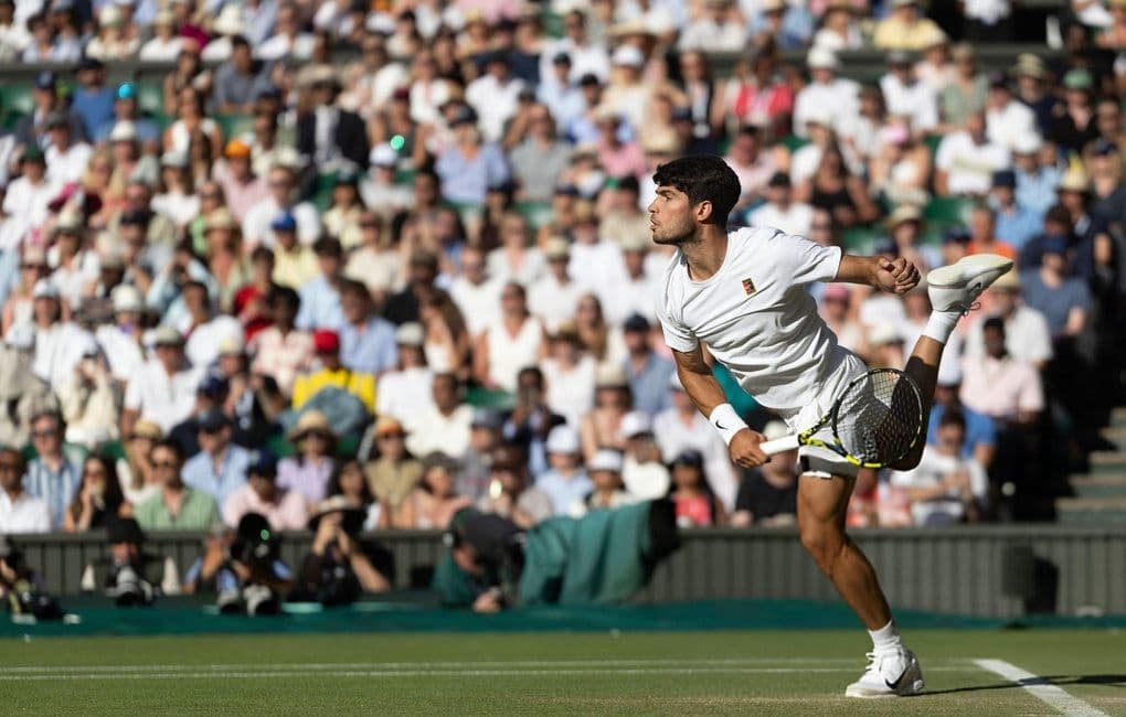 Carlos Alcaraz giao bóng trên sân cỏ Wimbledon, thể hiện sự thay đổi của mặt sân