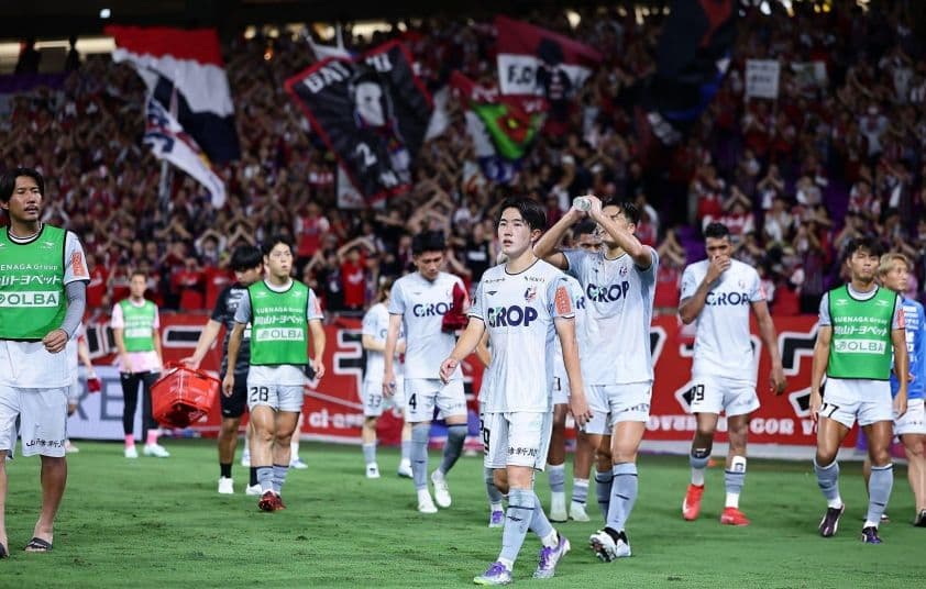 Các cầu thủ J-League và người hâm mộ trên sân cỏ, thể hiện sự gắn kết cộng đồng và DNA độc đáo của giải đấu.