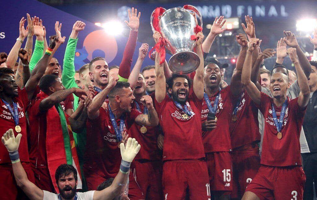 Các cầu thủ Liverpool ăn mừng chiến thắng với chiếc cúp Champions League, thể hiện giá trị của sự khó đoán và hành trình chinh phục.