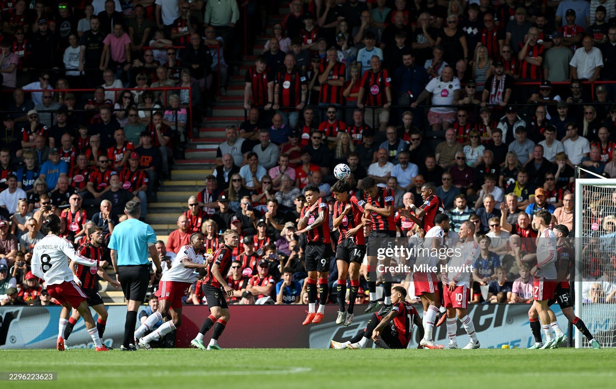 Các cầu thủ Liverpool và Bournemouth tranh chấp bóng trong vòng cấm, với khán giả trên khán đài Vitality Stadium.