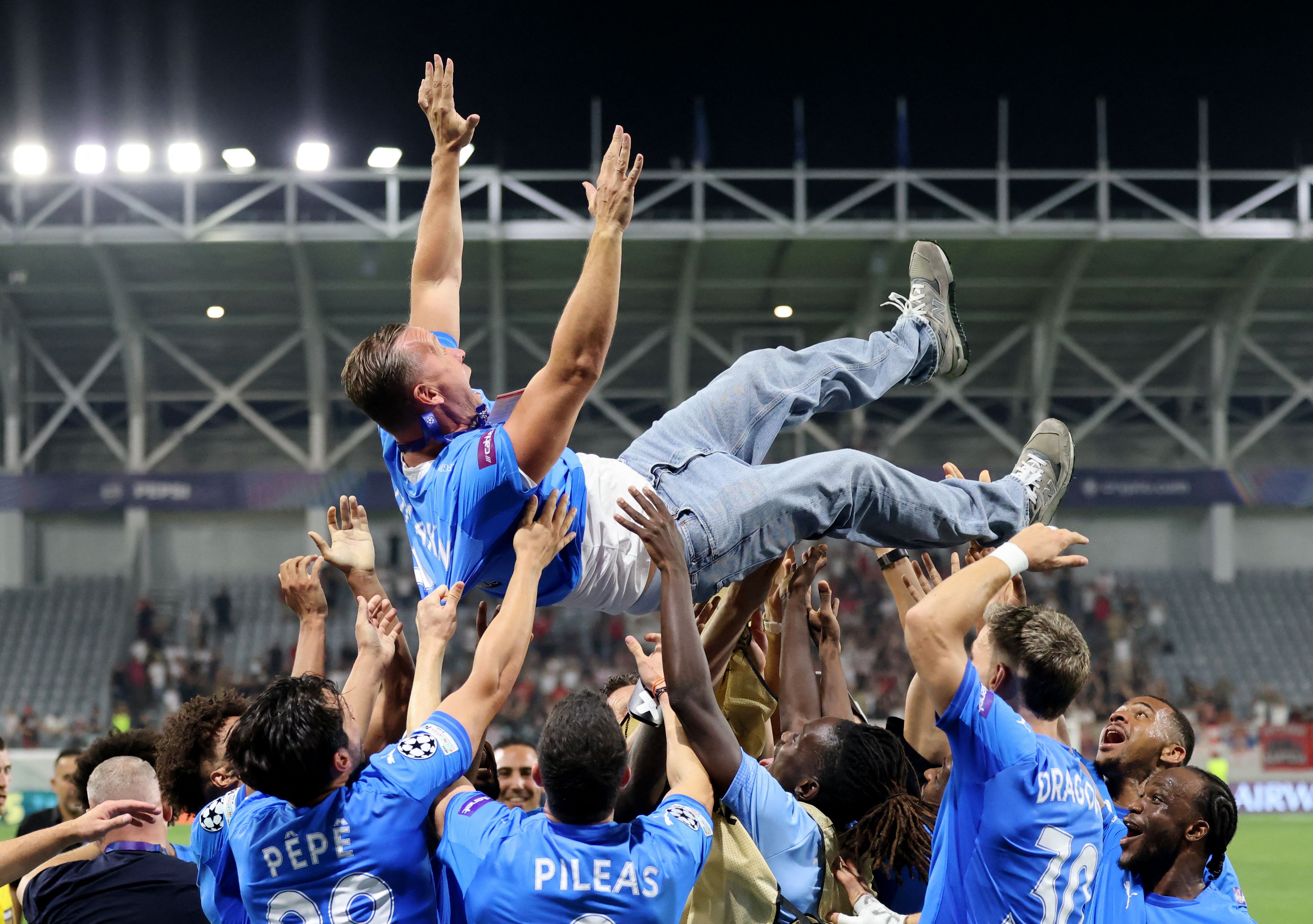 Các cầu thủ Pafos FC ăn mừng cuồng nhiệt bằng cách tung một người lên không, thể hiện tinh thần của đội bóng ngựa ô tại Champions League.