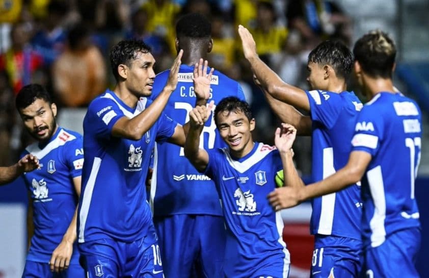 Các cầu thủ Pathum United trong trang phục màu xanh đang ăn mừng bàn thắng trên sân cỏ.