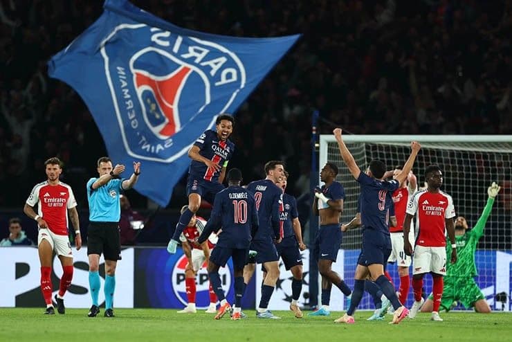 Các cầu thủ PSG ăn mừng chiến thắng với lá cờ đội, thể hiện không khí lễ hội và cảm xúc bùng nổ của Champions League.