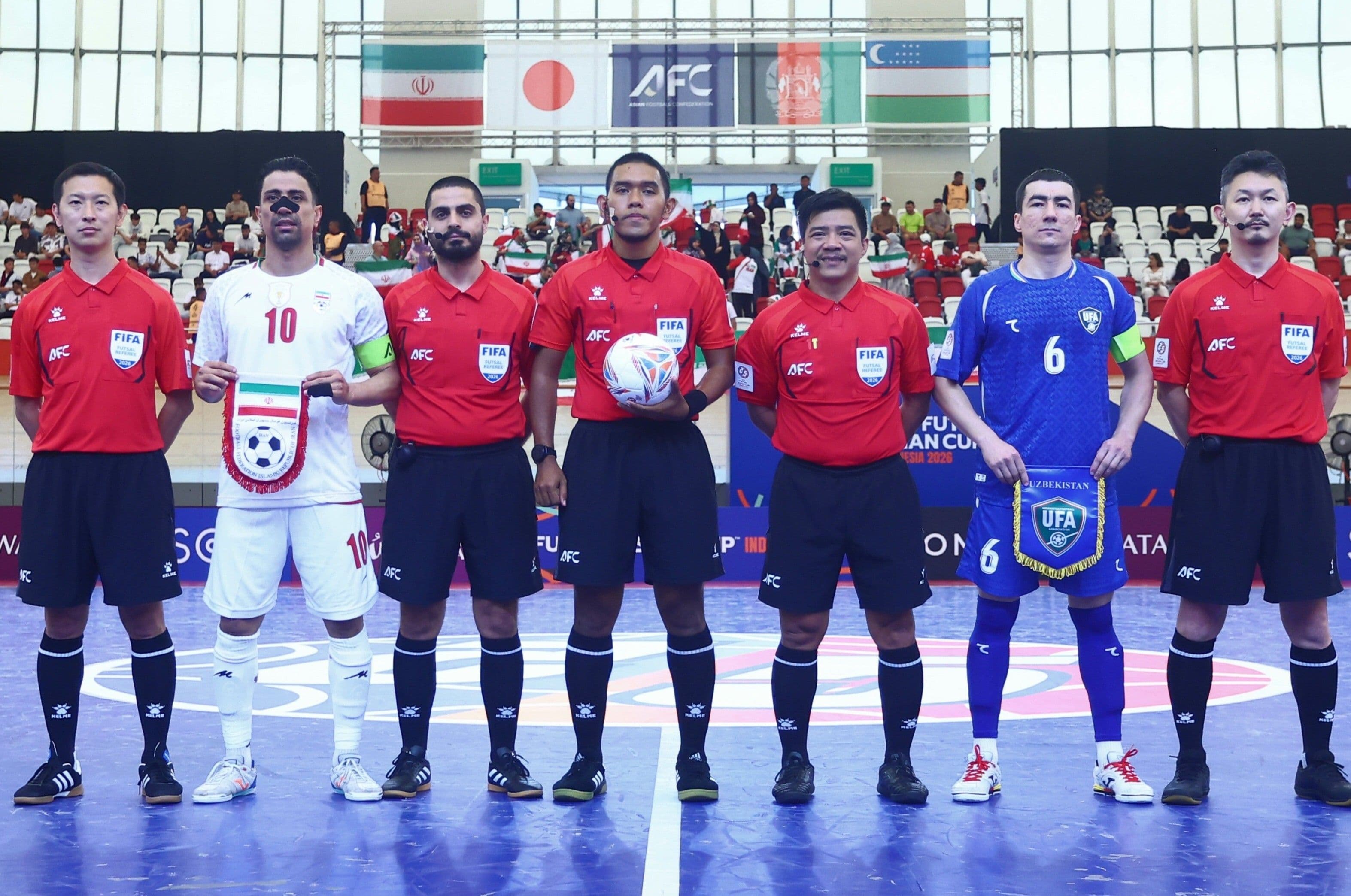 Các cầu thủ và trọng tài futsal xếp hàng trước trận đấu, với khán đài phía sau, thể hiện không khí của một trận đấu lớn tại Cúp Futsal Châu Á.