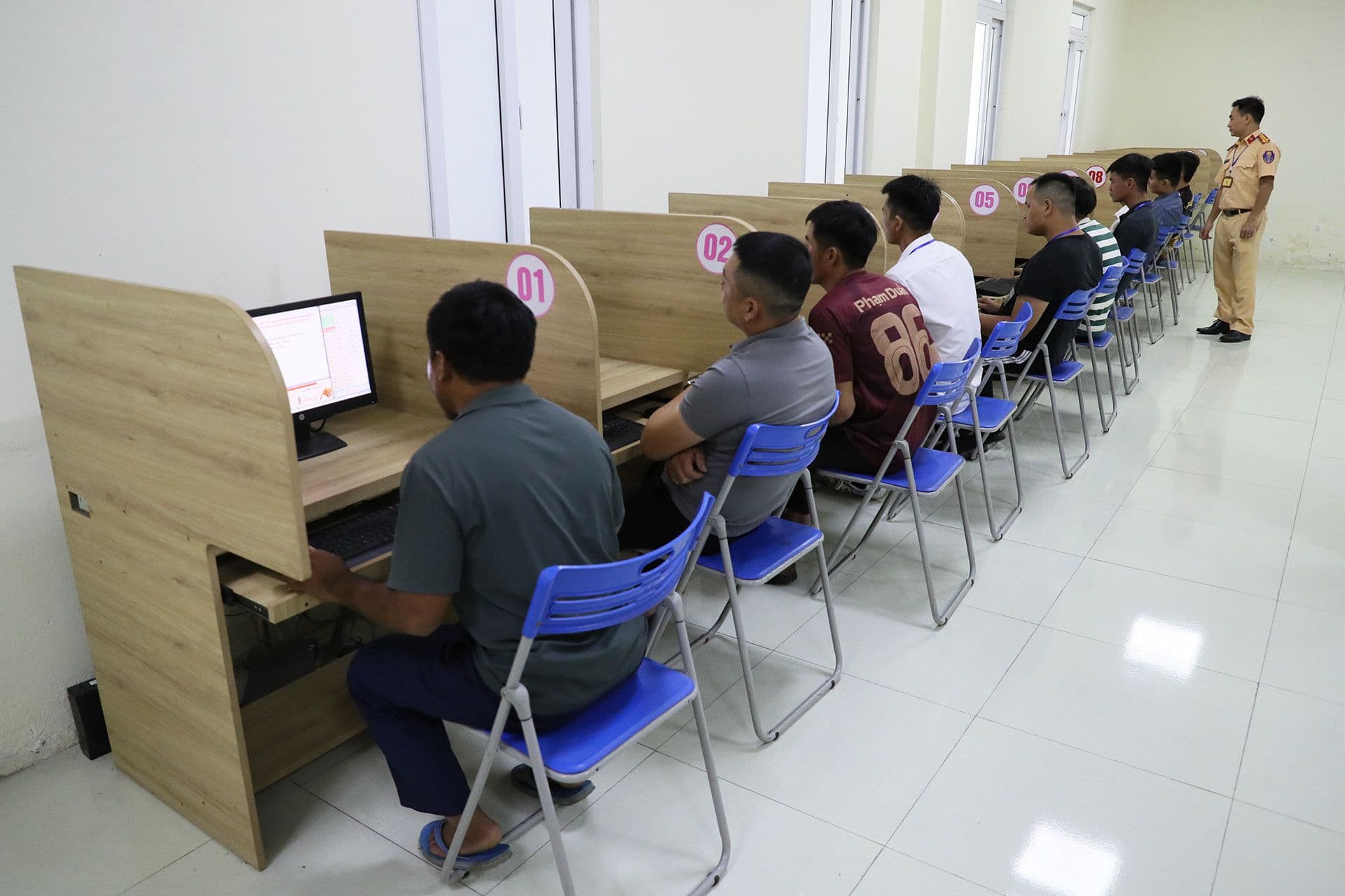Các học viên đang làm bài thi lý thuyết trên máy tính dưới sự giám sát, nhấn mạnh việc học thực chất thay vì học mẹo.