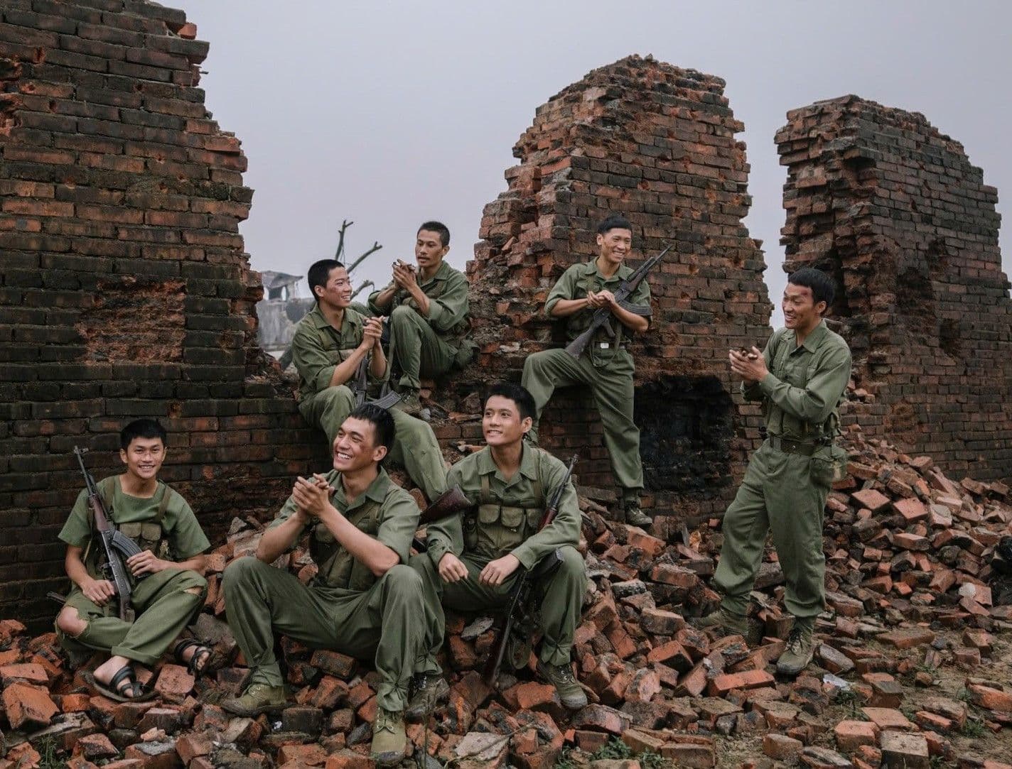 Các quân nhân trong phim 'Mưa Đỏ' ngồi giữa đống đổ nát, thể hiện tinh thần dân tộc và bối cảnh lịch sử của bộ phim.