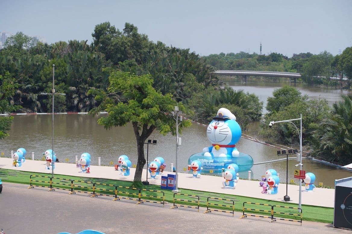 Các tượng Doraemon lớn nhỏ tại một sự kiện ngoài trời, tượng trưng cho sự trở lại và sức hút của Doraemon tại Việt Nam