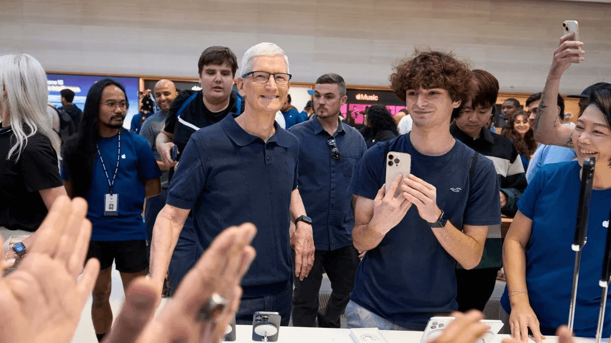 CEO Apple Tim Cook tương tác với khách hàng tại cửa hàng, một người đang cầm iPhone.