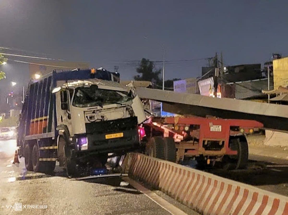 Chiếc xe chở rác bị hư hại nặng và tấm thép lớn rơi trên đường tại cầu Kênh Tẻ vào ban đêm sau vụ tai nạn.
