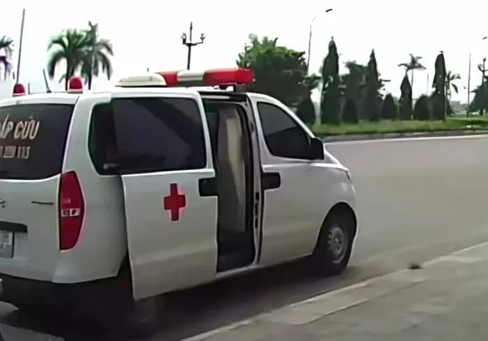 Chiếc xe cứu thương màu trắng với cửa sau mở, biểu tượng chữ thập đỏ, tượng trưng cho dịch vụ cấp cứu bị lợi dụng.