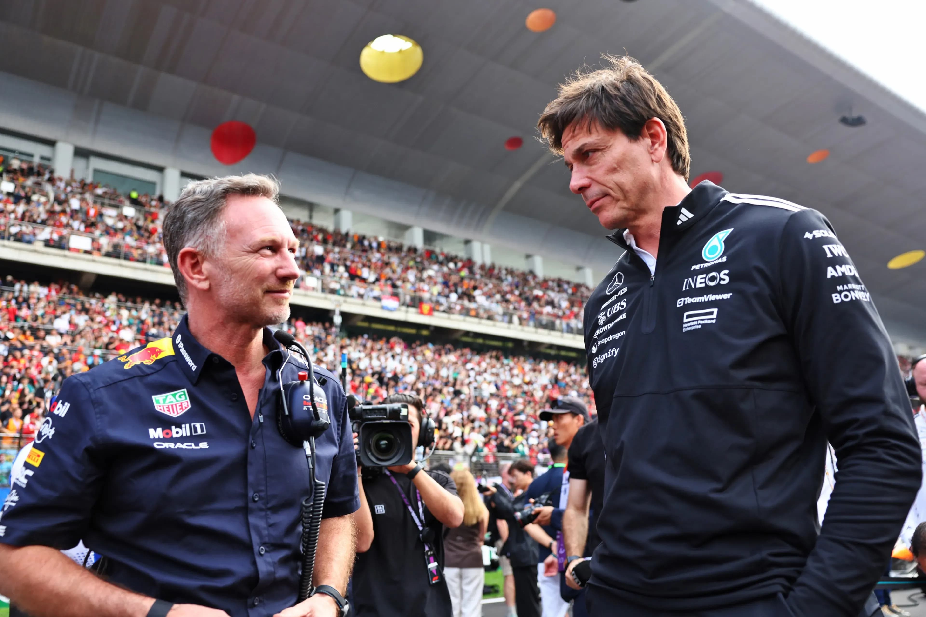 Christian Horner và Toto Wolff, hai lãnh đạo đội đua F1, trao đổi, tượng trưng cho những cuộc thảo luận và quyết định chiến lược định hình tương lai của Formula 1.