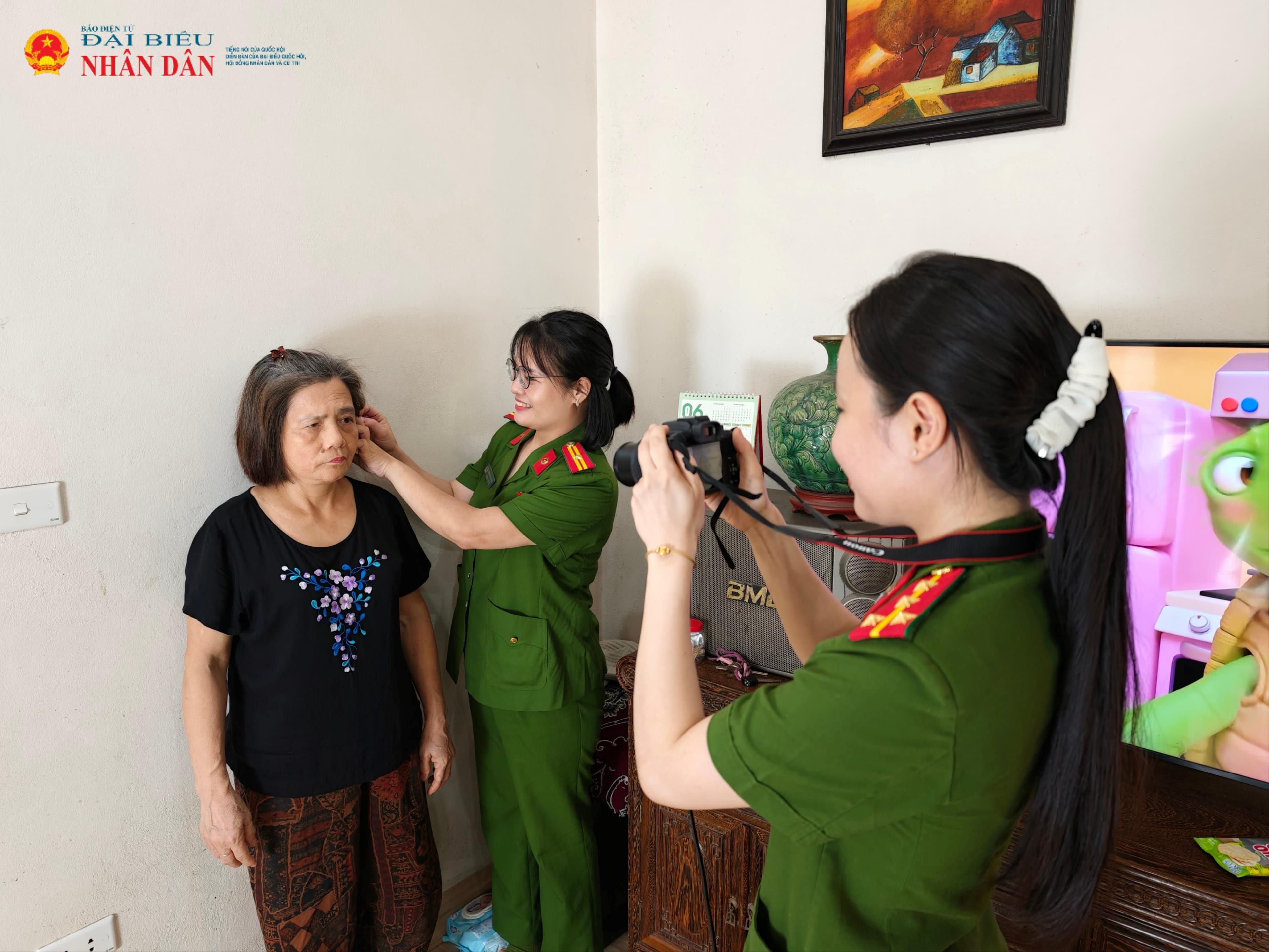 Cán bộ công an chụp ảnh cho người cao tuổi trong quá trình làm Thẻ Căn cước tại nhà.