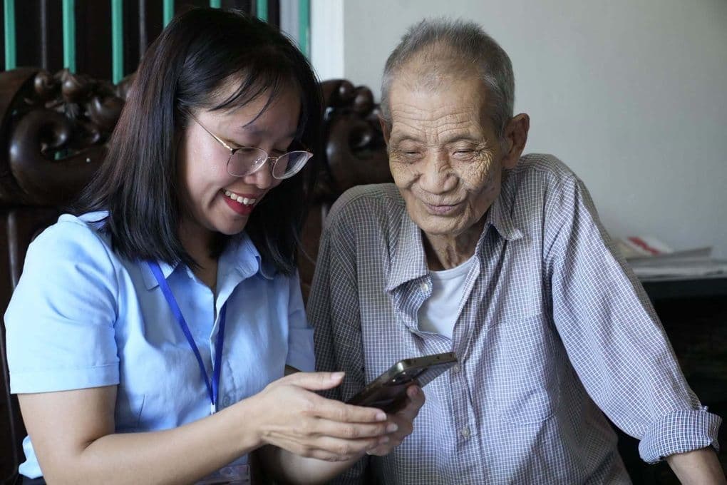 Cán bộ hướng dẫn người cao tuổi sử dụng ứng dụng VssID trên điện thoại, thể hiện sự hỗ trợ và chuyển đổi số trong hành chính công