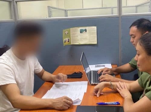 Cán bộ làm việc tại bàn, tượng trưng cho quá trình thẩm định và rà soát hành lang pháp lý cho nghệ thuật.