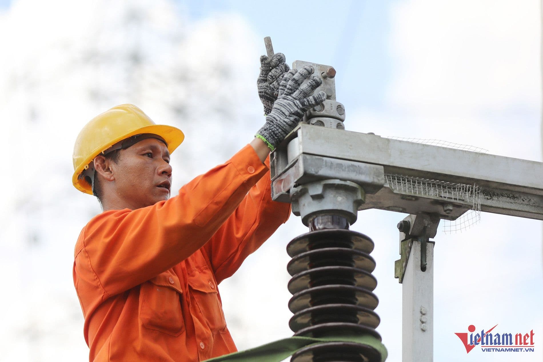 Công nhân điện lực đang kiểm tra thiết bị điện ngoài trời, tượng trưng cho nỗ lực quản lý lưới điện trong giờ cao điểm.