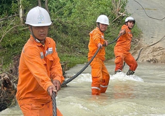 Công nhân điện lực miền Bắc đang kéo dây cáp qua vùng ngập lụt để khắc phục sự cố lưới điện sau bão Bualoi.