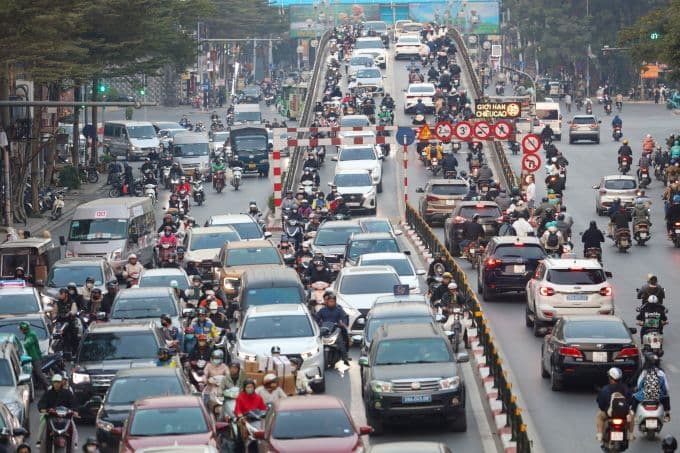 Cảnh giao thông đông đúc với nhiều xe máy và ô tô trên đường phố Hà Nội, thể hiện thách thức chuyển đổi phương tiện.