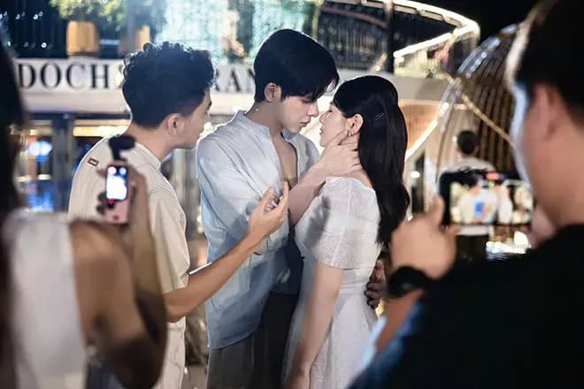 Cảnh hậu trường Denis Đặng và Việt Hoa quay nụ hôn dưới mưa, với nhiều thành viên ê-kíp và máy quay xung quanh.