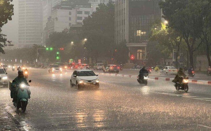 Cảnh đường phố Hà Nội ngập nước và xe cộ di chuyển trong cơn mưa lớn, minh họa thời tiết giông bão thất thường của thành phố.