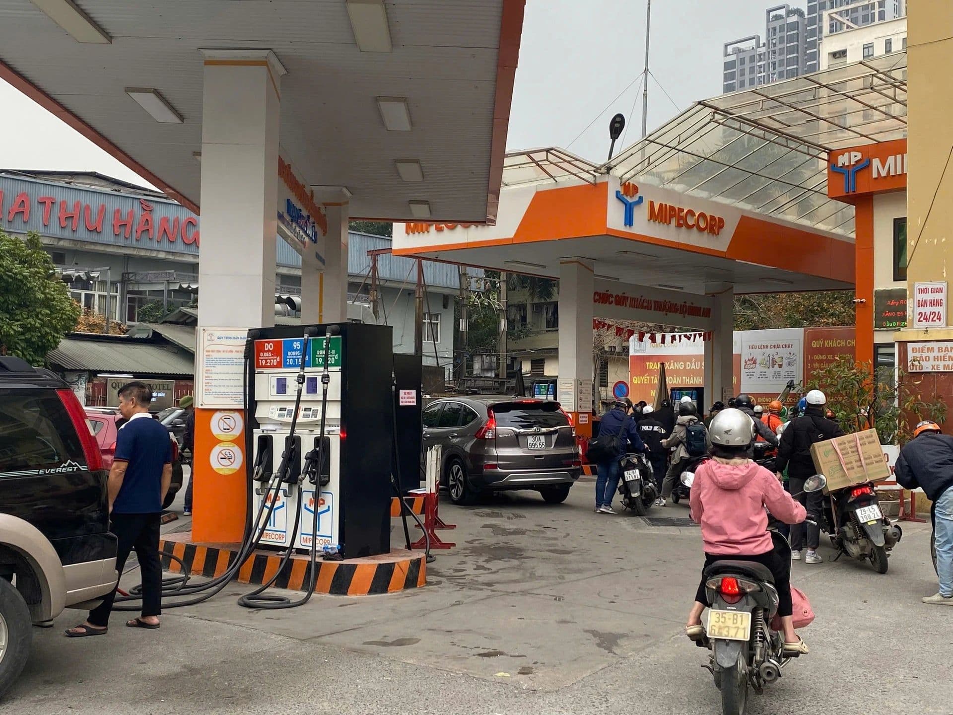 Cảnh người dân và xe cộ đang đổ xăng tại một trạm xăng, minh họa cho chủ đề giá xăng dầu và tác động đến đời sống.