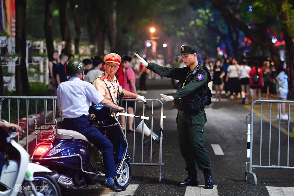 Cảnh sát giao thông hướng dẫn người dân đi xe máy tại khu vực cấm đường ở Hà Nội đêm trước Quốc khánh.